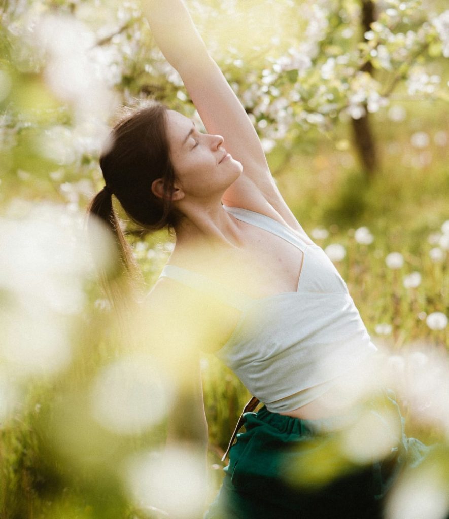 Woman stretching outdoors in sunlight, practicing 7 simple ways to manage anxiety with calming movement and mindful breathing.