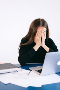 Woman participating in online cognitive behavioral therapy for anxiety, feeling stressed while using a laptop during a virtual CBT session.