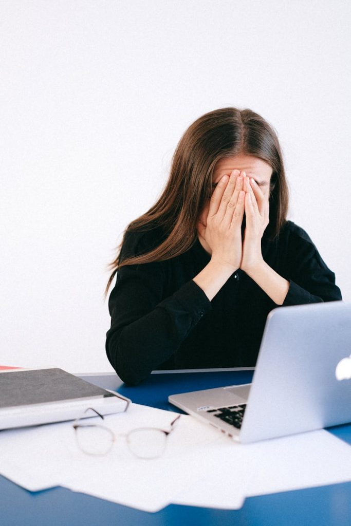 Woman participating in online cognitive behavioral therapy for anxiety, feeling stressed while using a laptop during a virtual CBT session.